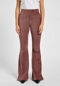 Pantalones de pana color rosa con campana, con costuras verticales, de cintura alta y un estilo ajustado. Presentan una textura suave y una abertura de pierna ancha en la parte inferior.