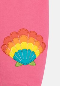 Rosa Stoff mit einem gestickten Muscheldesign in Orange, Gelb und Türkis, mit grünen Akzenten am Boden.