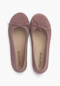 Ballerine in morbido suede malva con punta rotonda, delicato dettaglio con fiocco, e suole beige con nome del marchio stampato. Texture liscia, design semplice.