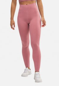 Leggings rosa de cintura alta, hechos de un material suave y elástico, con un diseño sin costuras y sin herrajes visibles.