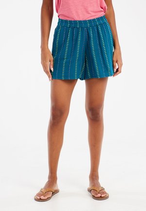 Teal shorts van lichtgewicht stof, met verticale strepen in groen, geel en roze. Elastische tailleband voor comfort. Sandalen complementeren de look.