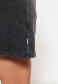 Shorts en coton gris avec une texture douce, présentant un ourlet cousu et une petite étiquette blanche sur le côté.