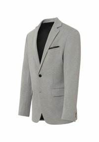 Blazer gris clair en tissu texturé, fermeture à un bouton, deux poches avant et doublure noire. Accent avec pochette noire.