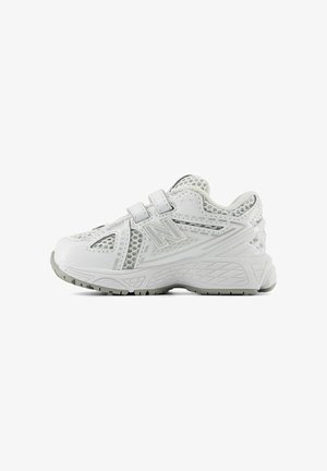 White athletic shoes with mesh design, adjustable straps, and textured grey accents. Thick rubber sole with patterned tread for grip.