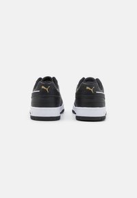 Black sports shoes with a smooth leather upper, white midsole, and black rubber outsole. Gold logo accent on the heel.