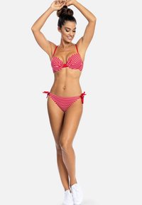 Czerwono-białe bikini w paski z biustonoszem na drutach i regulowanymi troczkami po bokach majtek. Gładka tekstura, minimalistyczny design.