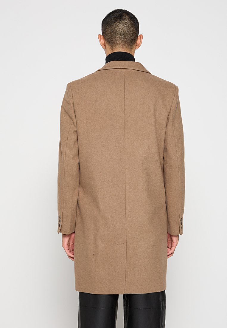 Cappotto in lana marrone con taglio dritto, colletto a scaldacollo e maniche lunghe. Presenta due bottoni sui polsini e una texture liscia.