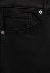 Črne jeans hlače iz denima z sprednjo žepono, vidnim šivom in kovinsko gumbom. Gladka tekstura z rahlo sijajem.