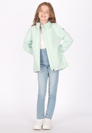 Menta zöld, puha héjú dzseki magas gallérral, cipzáros elülső résszel, oldalsó zsebekkel és fekete logóval. Fehér ing és világoskék farmer fölé öltözve.