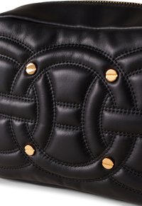 Borsa nera in pelle trapuntata con motivi circolari, cuciture visibili e dettagli in metallo dorato. Texture liscia e chiusura con zip.