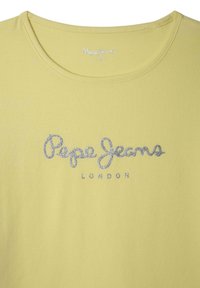 Geltona marškinė su apvaliu kaklu, ant krūtinės su sidabriniu blizgučių užrašu "Pepe Jeans LONDON". Lygi audinio tekstūra.