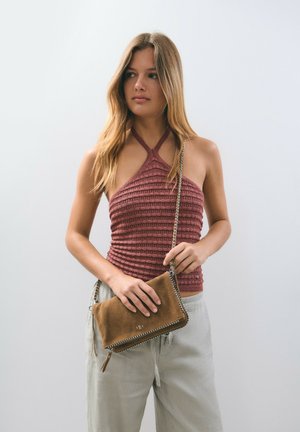 Top de halter tejido en burdeos con rayas texturizadas, combinado con un bolso cruzado de ante marrón que presenta una cremallera plateada y detalles de logo.