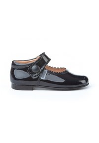 Zapato Mary Jane de charol negro con borde festoneado, correa ajustable y acento de botón redondo. Con tacón bajo y textura suave.