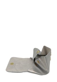 Petite pochette en cuir argenté ouverte avec trois boutons-pression en laiton et un intérieur en daim doux visible.