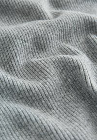 Pelēks ribots audums ar mīkstu tekstūru, ar vertikālām svītrām un nelielu stiepšanās pakāpi, parādot maigas locījumus un plūstošus krājumus.