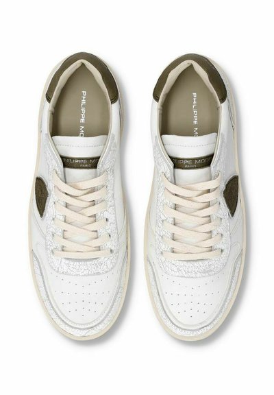 Hvide sneakers med et tekstureret læderdesign, beige snørebånd og en brun detalje nær hælen. Perforeringer på tåområdet for ventilation.