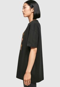 Schwarzes Oversized-T-Shirt aus Baumwolle mit kurzen Ärmeln, das auf der Vorderseite eine abstrakte, mehrfarbige Grafik zeigt.