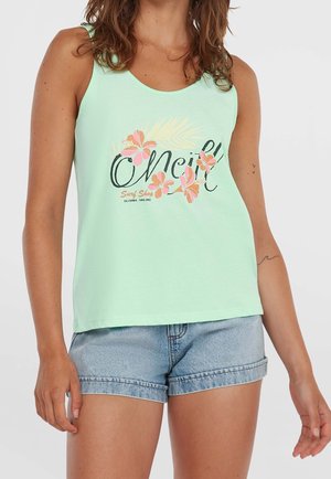 Mujer vistiendo una camiseta sin mangas verde claro con diseño floral rosa y texto "O'Neill Surf Shop California Santa Cruz", combinada con shorts de mezclilla azul.