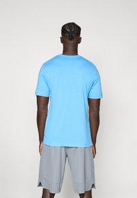 Blå kortærmet T-shirt lavet af bomuld, med runde halsudskæring. Sammen med grå træningsshorts, der viser en afslappet pasform og sideslidser.