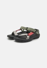 Black sandals with green and red adjustable straps, rubber soles, and a textured footbed. Features a sturdy design for outdoor wear.