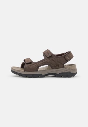 Sandalia al aire libre de Skechers, de color marrón, con los dedos al aire, correas ajustables, plantilla acolchada de color beige y suela robusta en negro y gris.