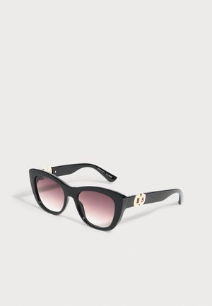 Schwarze Cat-Eye-Sonnenbrille mit pinken Verlaufsgläsern und goldenen dekorativen Akzenten an den Bügeln, auf hellem Hintergrund präsentiert.