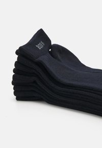 Schwarze Baumwollsocken gestapelt mit gerippten Bündchen, die ein kleines Logo am oberen Rand aufweisen. Glatte Textur, einheitliche Form, keine sichtbaren Muster.