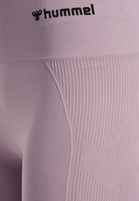 Leggings lilla chiaro realizzati in tessuto elasticizzato, con un design a coste testurizzato e logo Hummel in vita.