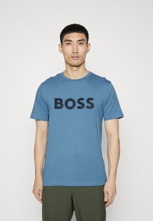 Camiseta de algodón azul con un gran logo negro "BOSS" en la parte delantera. Manga corta y cuello redondo con una textura suave.