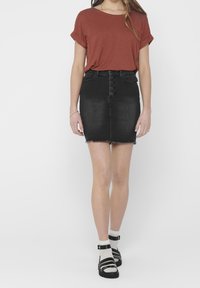 Czarna spódnica dżinsowa z postrzępionym dołem i zapinana na guziki, w zestawieniu z rudawą koszulą z krótkim rękawem oraz czarnymi sandałami na paski.