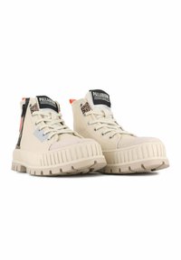 Stivali beige alta di Palladium con suole spesse e rigate, dettagli con stampa leopardata, zip laterale e etichette con logo sulla linguetta.