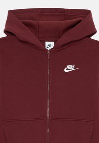 Sweatshirt de capuz marrom com fecho, com um bolso frontal e um logótipo da Nike em branco. Textura suave, capuz ajustável e detalhes de costura precisos.