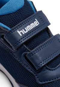 Marinblå sneaker med mesh-tyg och läderdetaljer. Har kardborreband och blå detaljer. Förstärkt sömnad runt kanterna.