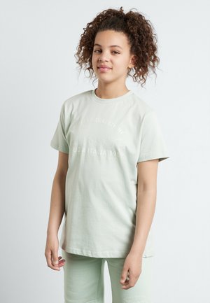 Camiseta de algodón verde claro con mangas cortas, que presenta un estampado de logo texturizado en el frente. Combinada con pantalones cortos verdes claros a juego.