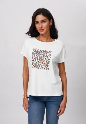 T-shirt en coton blanc avec un col rond, arborant un graphique imprimé léopard dans des teintes de marron, noir et orange. Manches courtes.