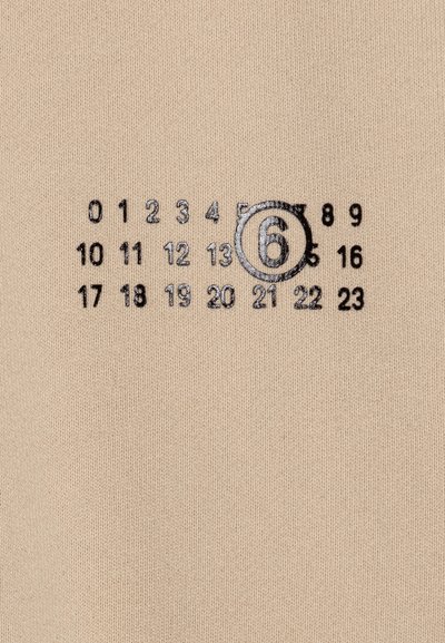 Beige tyg med en strukturerad stickning. Tryckta svarta siffror arrangerade i ett rutnät, med siffran 6 som är tydligt inringad.