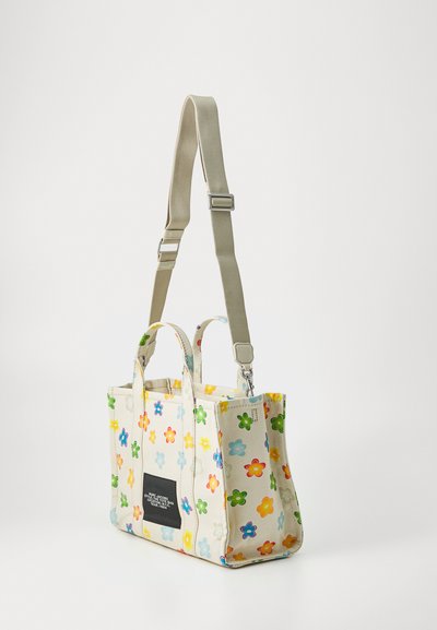 Canvas tote bag med fargerike blomsterdesign, doble topphåndtak og justerbar stropp. Har en svart logo-lapp foran.