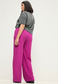 Fuchsia wijde broek met een gestructureerde afwerking, gecombineerd met een losse, grijze T-shirt. De outfit heeft een ontspannen pasvorm en een casual ontwerp.