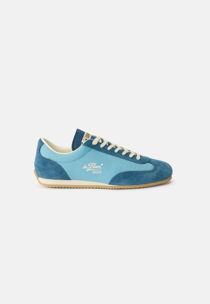Blauer Wildleder- und Stoff-Sneaker in Low-Top-Design mit beigen Schnürsenkeln, Gummisohle und "le Fleur Jogger"-Logo an der Seite.