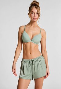 Sæt med lysegrøn bh og matchende shorts; bh'en har formede kopper og justerbare stropper, mens shortsene har elastik i taljen og snøre.