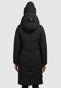 Zwarte gewatteerde jas met een chevronpatroon, voorzien van een capuchon en een rits. Brei-beanie zichtbaar bovenaan, wat warme benadrukt.
