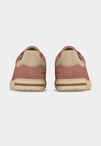 Ζευγάρι ροζ σουέντ αθλητικά παπούτσια με μπεζ λεπτομέρειες στη φτέρνα και μπεζ σόλες, εμφανιζόμενα από πίσω σε λευκό φόντο.