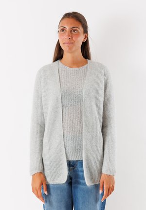 Cardigan aperto grigio chiaro con una texture a coste; tessuto lavorato a maglia morbido; abbinato a un top di chiffon grigio chiaro e jeans blu.