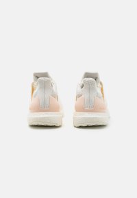 Sportschuhe mit weißem Mesh-Obermaterial, sanften rosa Akzenten an der Ferse und einer strukturierten weißen Zwischensohle. Verfügen über verstärkte Fersenlaschen und Dämpfung.