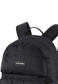 Svart ryggsäck med vadderade, justerbara remmar och ett handtag på toppen. Har en zippered framficka och en logotypapplikation på frampanelen.