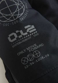 Schwarzer Stoff mit metallisch grauem bedrucktem Text, einschließlich "012 SYSTEM•REBOOT 1000," Symbolen und "NUR VORWÄRTS BEWEGEN." Glatte Textur.