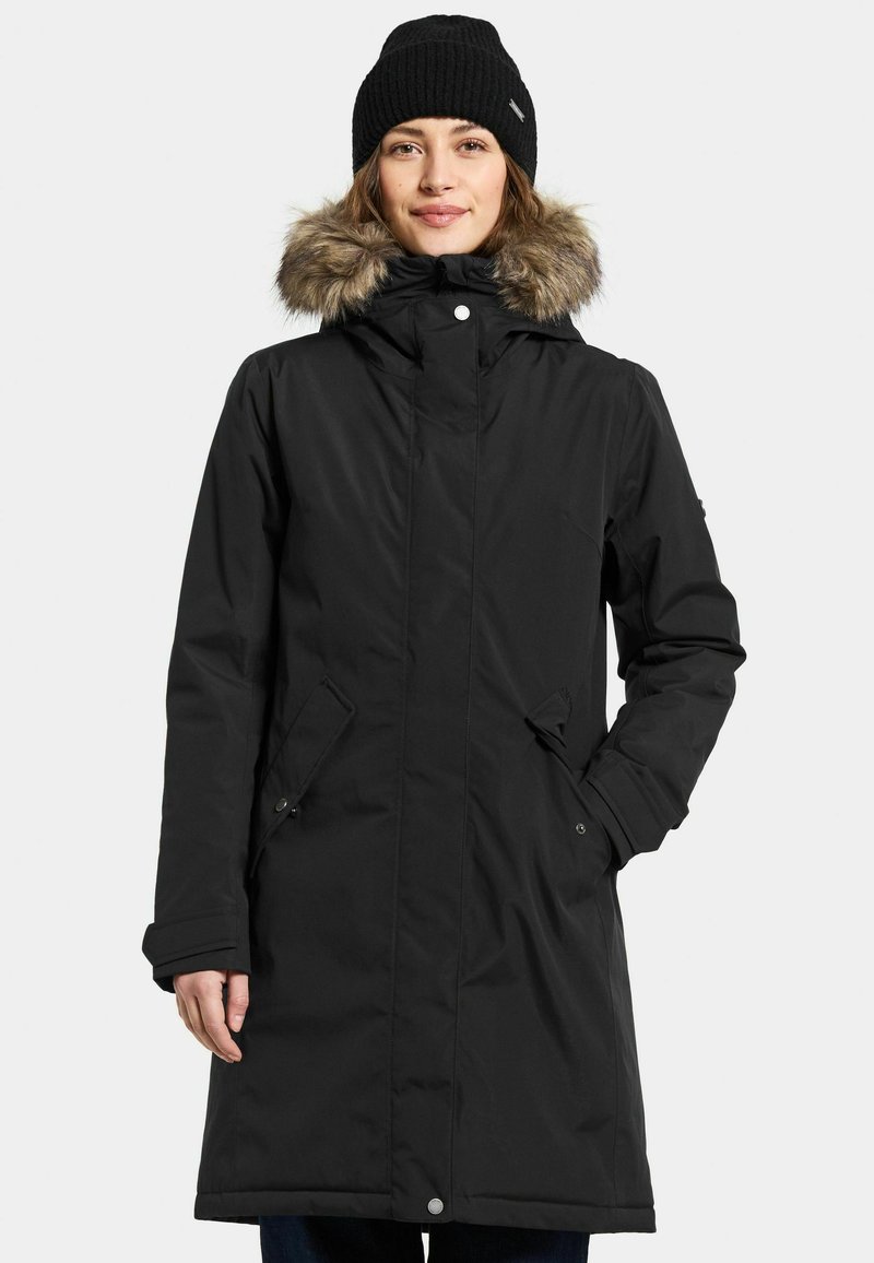 Zwarte waterdichte parka met een met bont gevoerde capuchon, voorzakken en knoopsluitingen. Heeft een rechte snit en een gebreide ribbeanie.