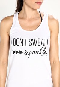 Débardeur blanc avec l'inscription « I DON’T SWEAT, I sparkle » en lettres noires, accompagné de trois icônes de flèches noires. Tissu en coton doux.