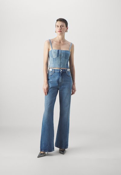 Lys blå denim cropped topp med tynne stropper og knappert detaljer, kombinert med høy midje, utsvingte jeans. Har sølvdetaljer på jeansene.