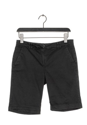 Pantalones cortos negros hasta la rodilla colgados en una percha negra, con trabillas para cinturón, cremallera frontal y bolsillos laterales sobre un fondo blanco.